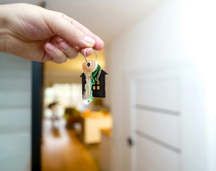 Chave de imóvel sendo entregue após regularização da propriedade, ilustrando o procedimento de adjudicação compulsória extrajudicial.